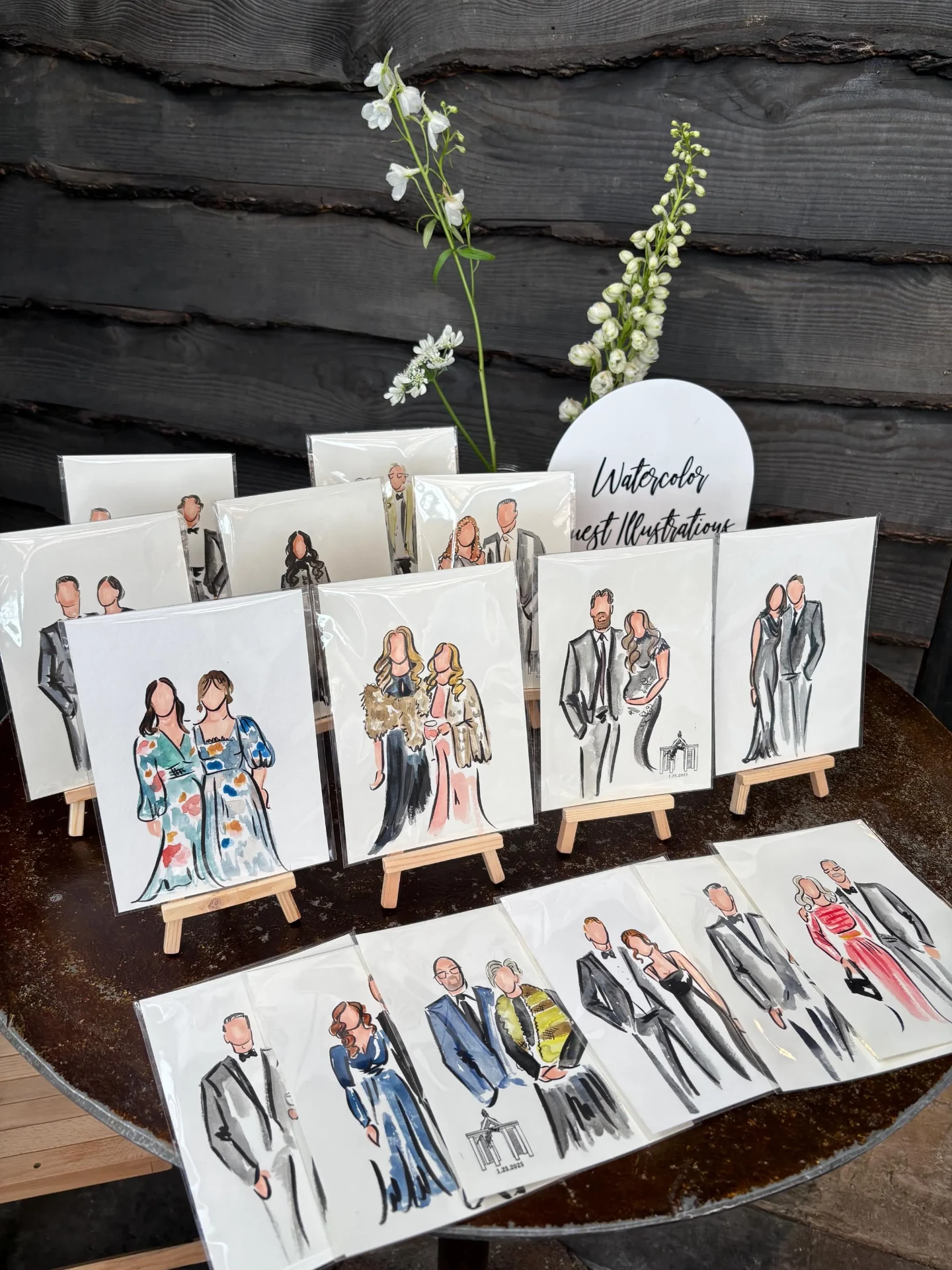 A table of 5x7 watercolor guest caricatures displayed on small wooden easels