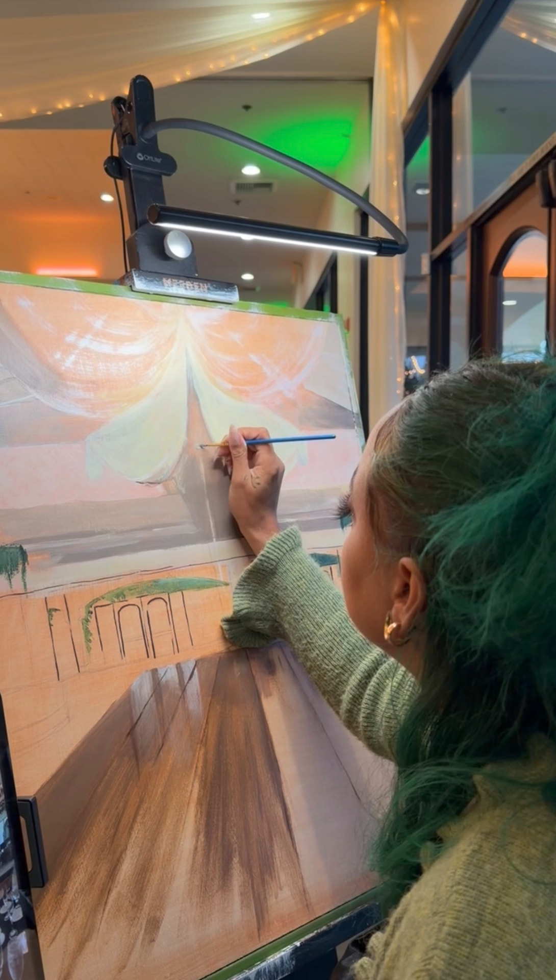 Chaleuh at her easel blocking in a wedding painting at the reception