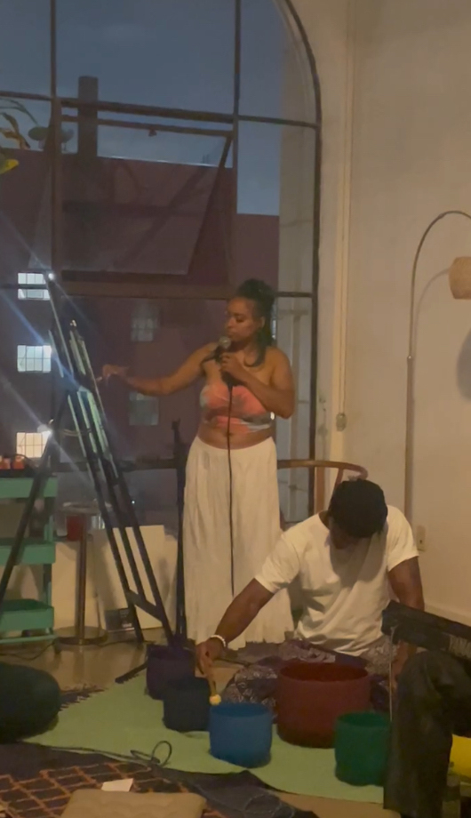 Chaleuh singing beside her easel during a live art and sound performance