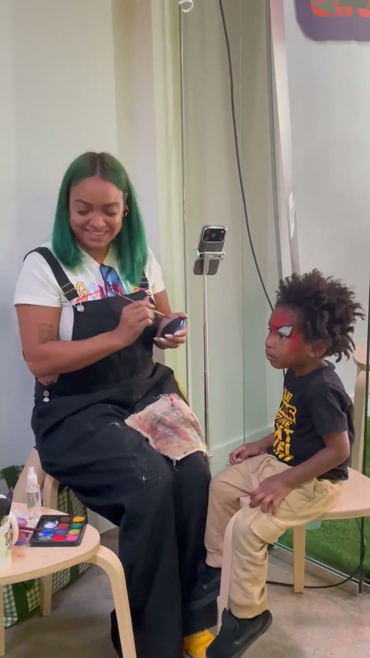 Chaleuh painting a red superhero mask onto a young guest