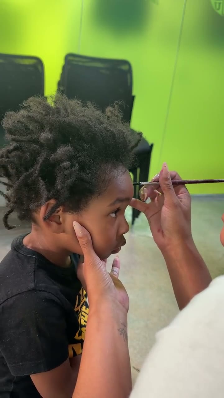 Chaleuh hand painting a design onto a young guest's face