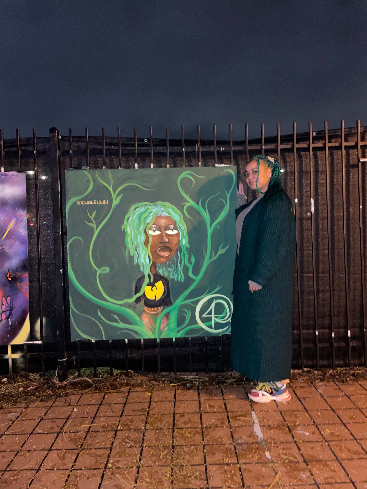 Chaleuh at night beside her painted panel of a woman wrapped in green vines