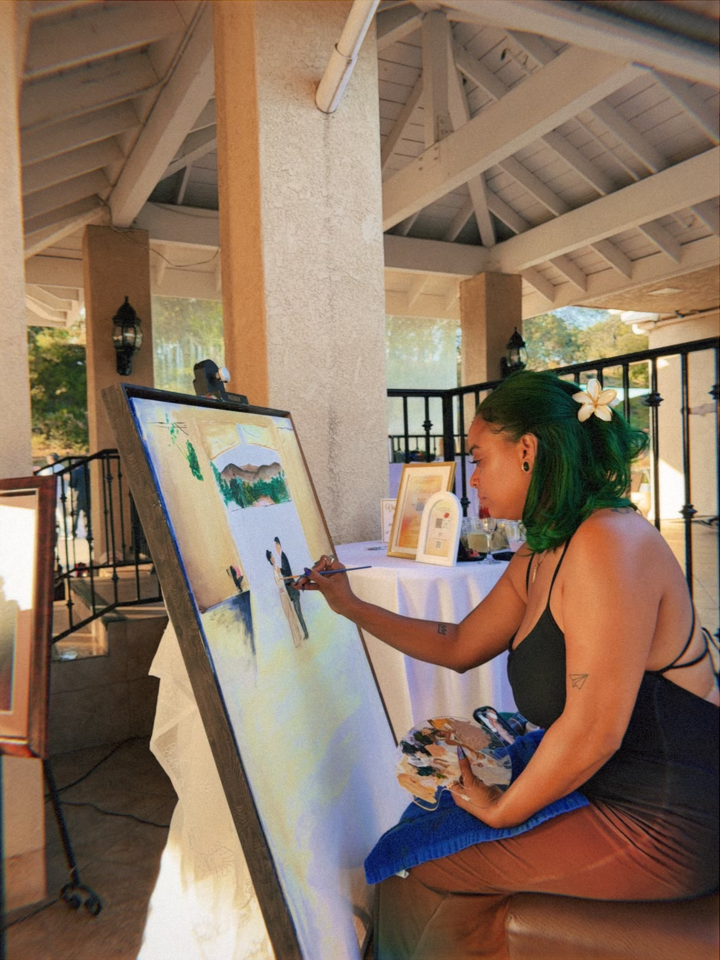 Chaleuh painting at an easel during a golden-hour celebration